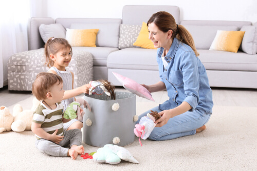 Madre recogiendo muñecos con sus hijos