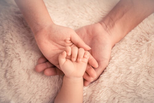 Mano de bebé sobre la mano de una madre para representar el vínculo de apego
