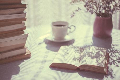 mesa con café y libros acumulados representando el Tsundoku