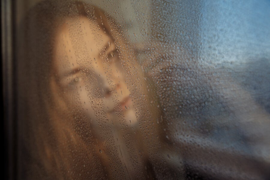 Mujer mirando lluvia a través de la ventana.