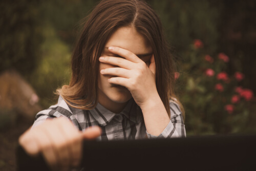 Mujer tapándose la cara por amenazas digitales