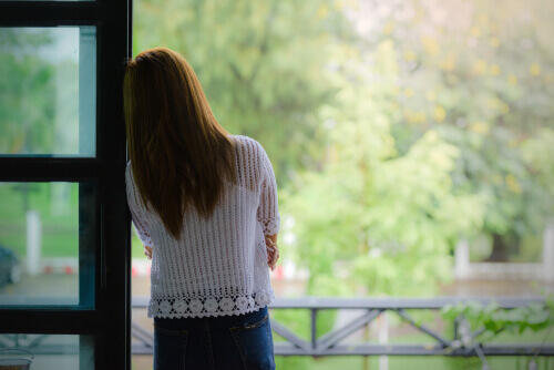 Mujer en la ventana pensando en la maternidad