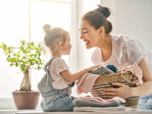 Niña recogiendo la ropa con su madre
