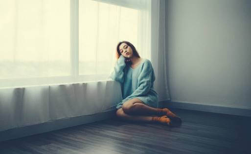 Chica junto a ventana representando cómo ayudar a tu cerebro a manejar el contexto de una pandemia