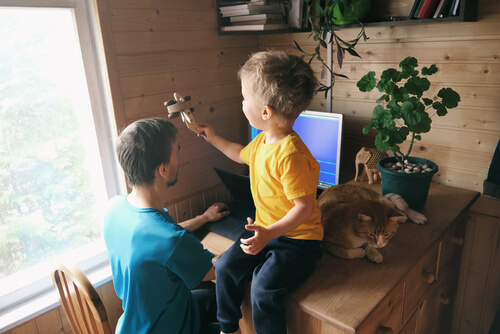 Niño jugando mientras su padre trabaja en casa