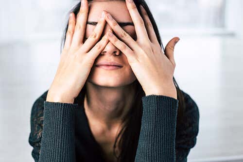 Mujer estresada con las manos en la cara y la mente en crisis