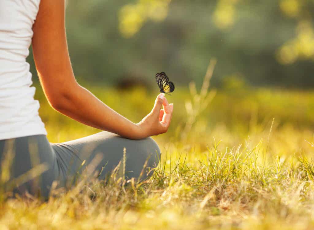 Vrouw mediteert met een vlinder op haar hand