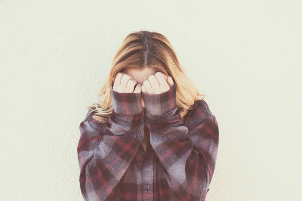 Adolescente tapándose la cara por sentimientos de vergüenza