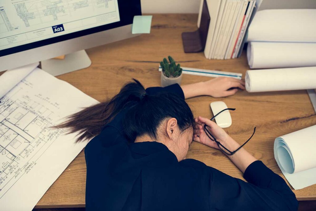 Mujer acostada en una mesa preguntándose ¿Por qué no puedo dejar de postergar?
