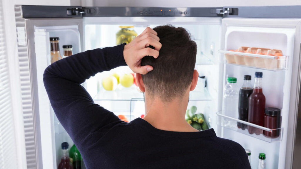 Hombre ante nevera abierta que sufre ansiedad por comer