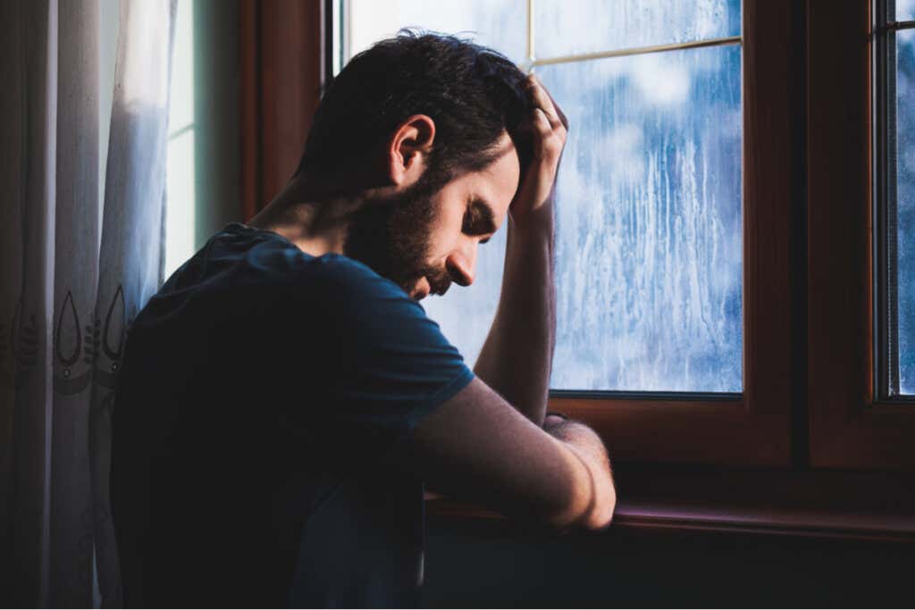 Uomo triste in una finestra che ha bisogno dei trattamenti più efficaci per la dipendenza emotiva