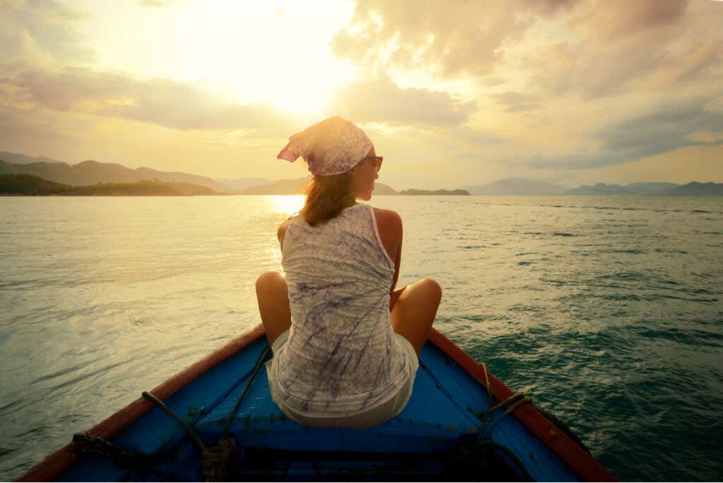 Mujer en una barca al atardecer dejando de Rumiar pensamientos