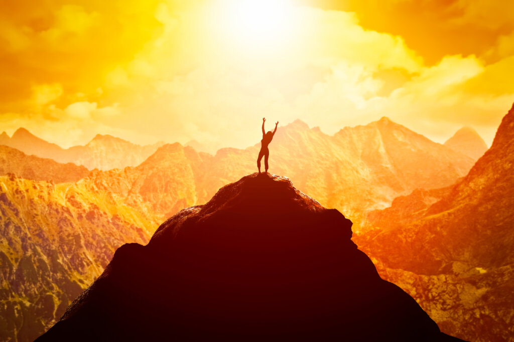 Frau auf einem Berggipfel pflegt das richtige Mindset