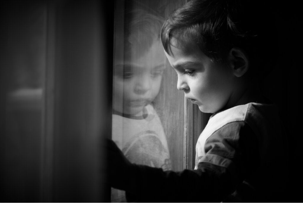 Trist barn som ser ut av vinduet for å representere hvordan barndomstraumer dukker opp på hjerneskanninger
