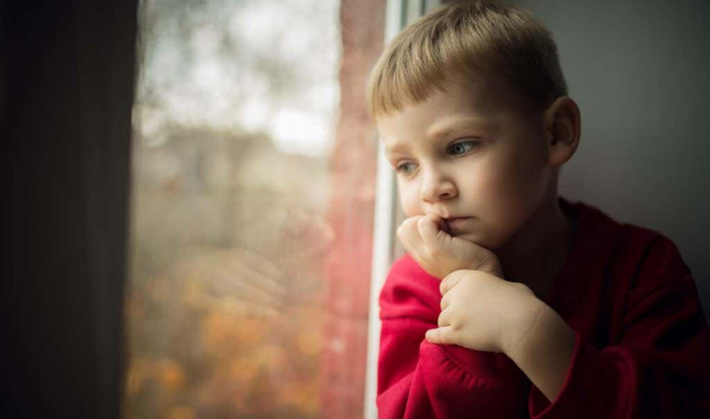 Smutny chłopiec patrzy przez okno