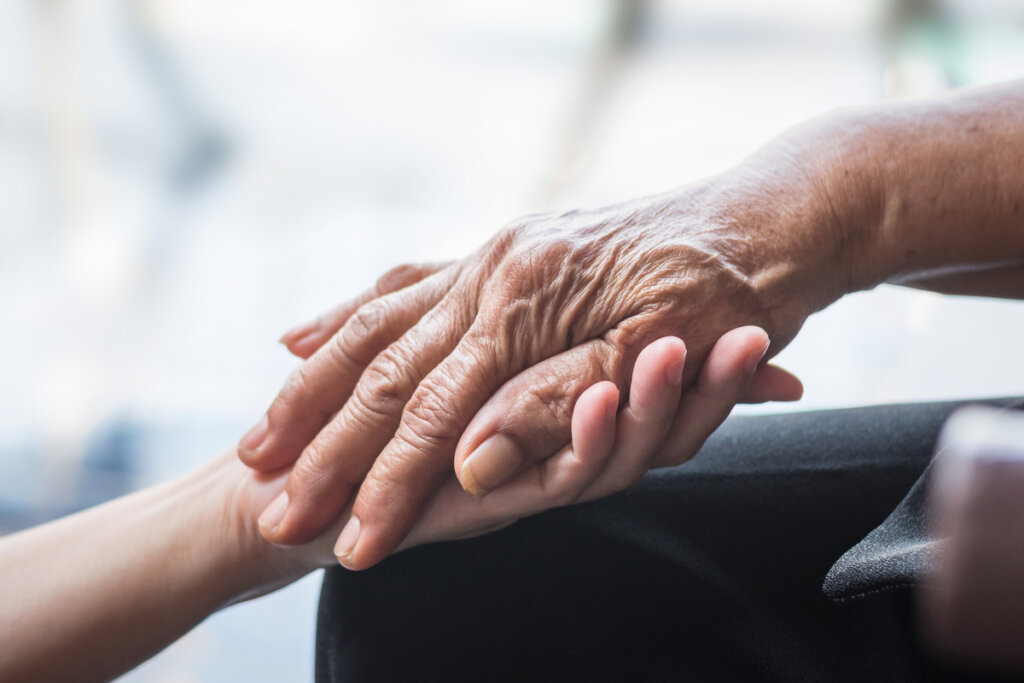 Person holding the hands of an older person