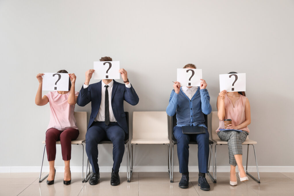 Personas con un cartel con una interrogación sobre la cara