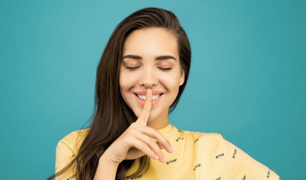 Fille faisant le geste du silence pour symboliser les personnes qui parlent peu