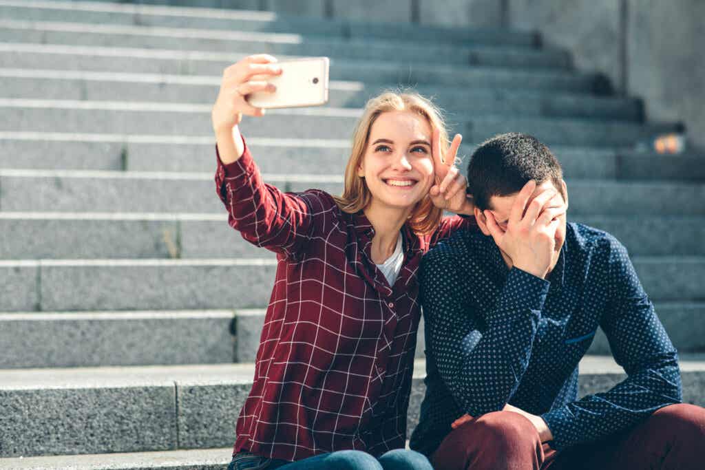 Chica haciéndose un selfie mientras su novio no quiere