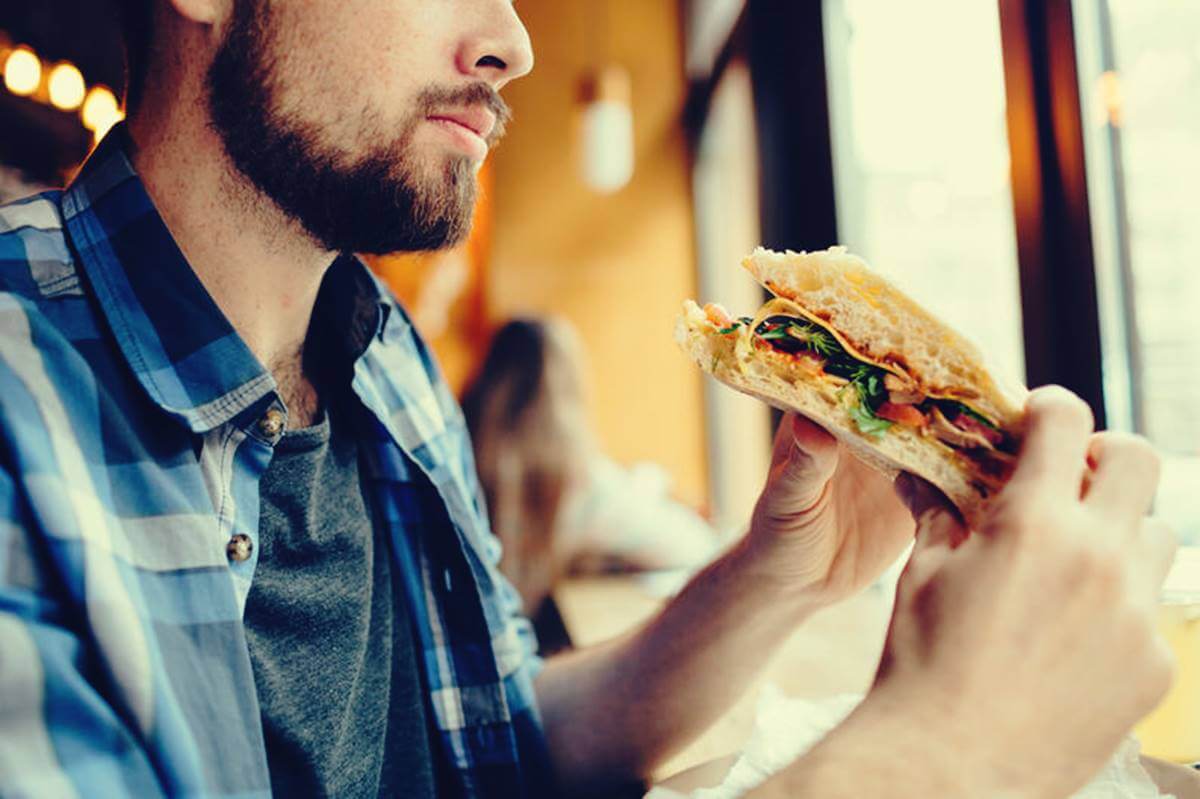 Hombre con bocadillo en las manos preguntándose por qué tengo hambre a todas horas