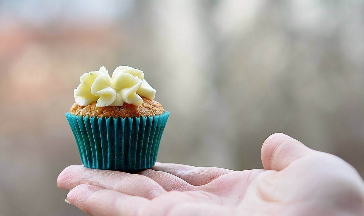 Mano sujetando muffin representando la adicción al azúcar