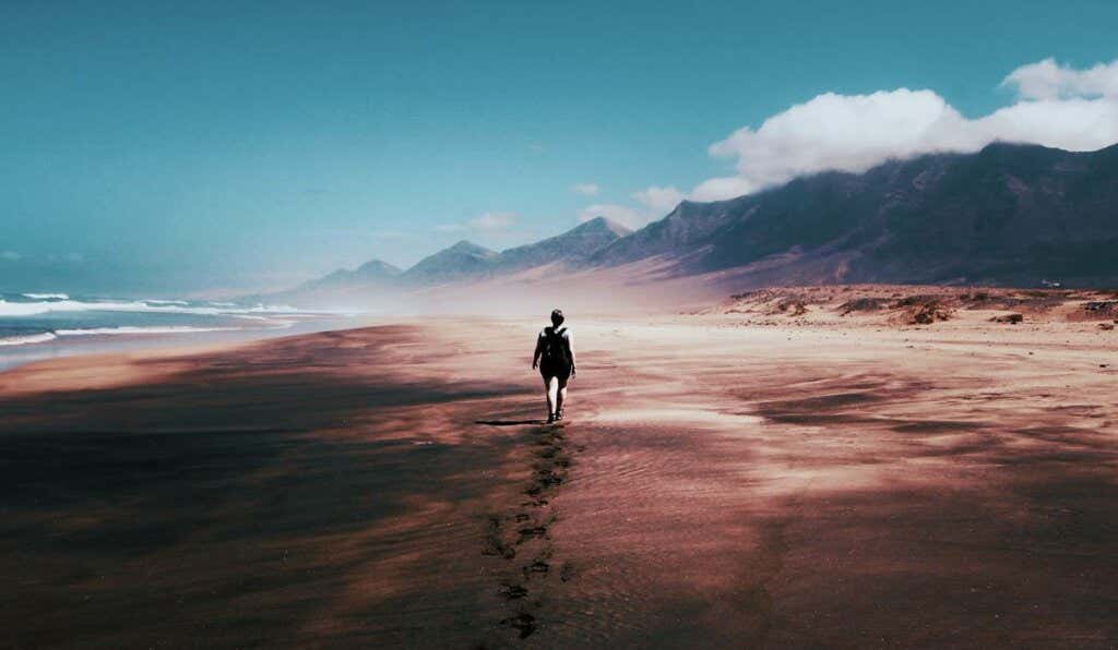 Iemand loopt over een verlaten strand