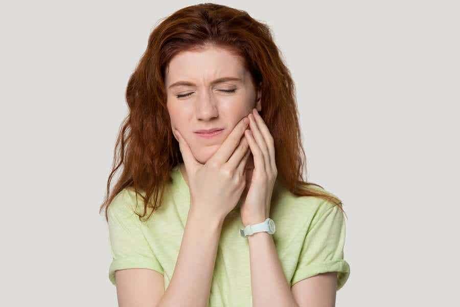 mujer que se coge la mandíbula porque sufre estrés y síndrome de tensión temporo-mandibular