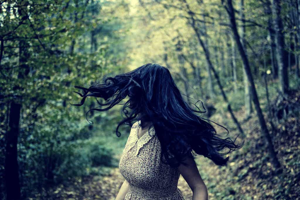 Nainen juoksee metsässä peläten.