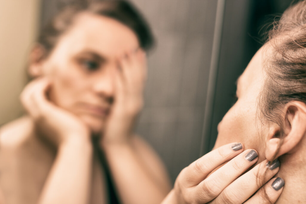Mujer triste mirándose al espejo