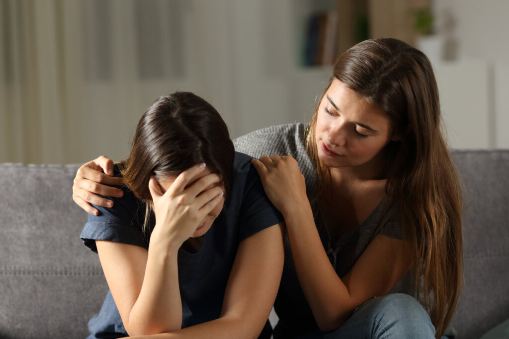 Chica triste por duelo con su amiga consolándola