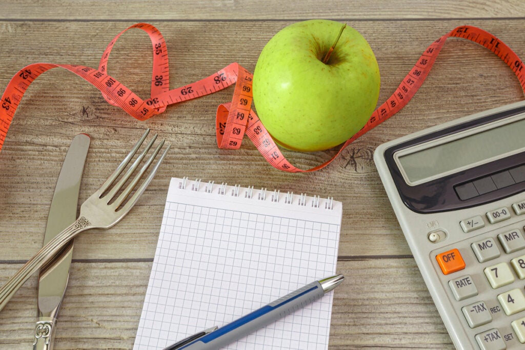 Caderno e calculadora para anotar as calorias da maçã