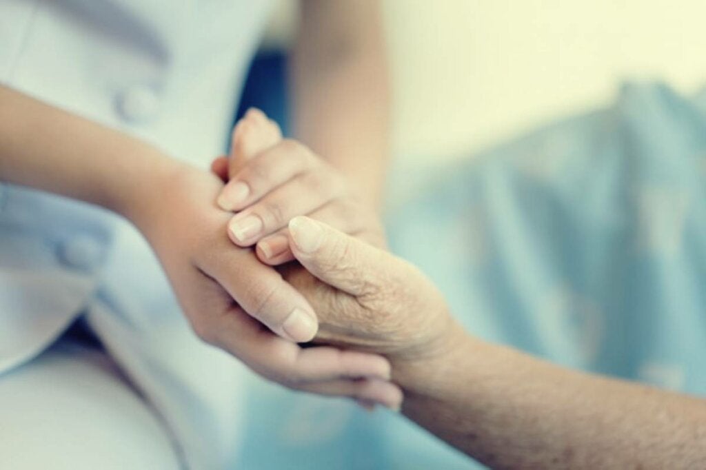 Persona cogiendo mano de anciano para representar la necesidad de ayudar a un anciano maltratado