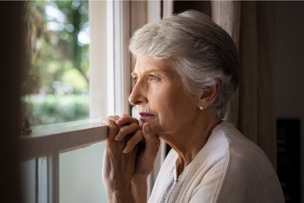 Mujer mayor mirando por la ventana