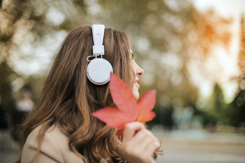 Chica con auriculares y hoja representando cómo afrontar la astenia otoñal