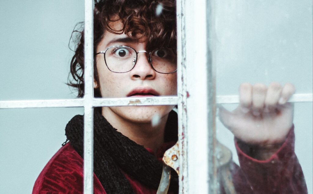 Chico tras ventana que siente estupor