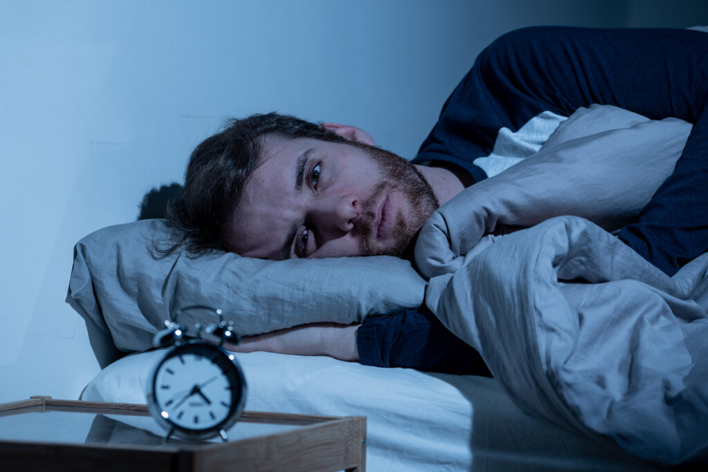 Homme souffrant d'insomnie en regardant l'horloge