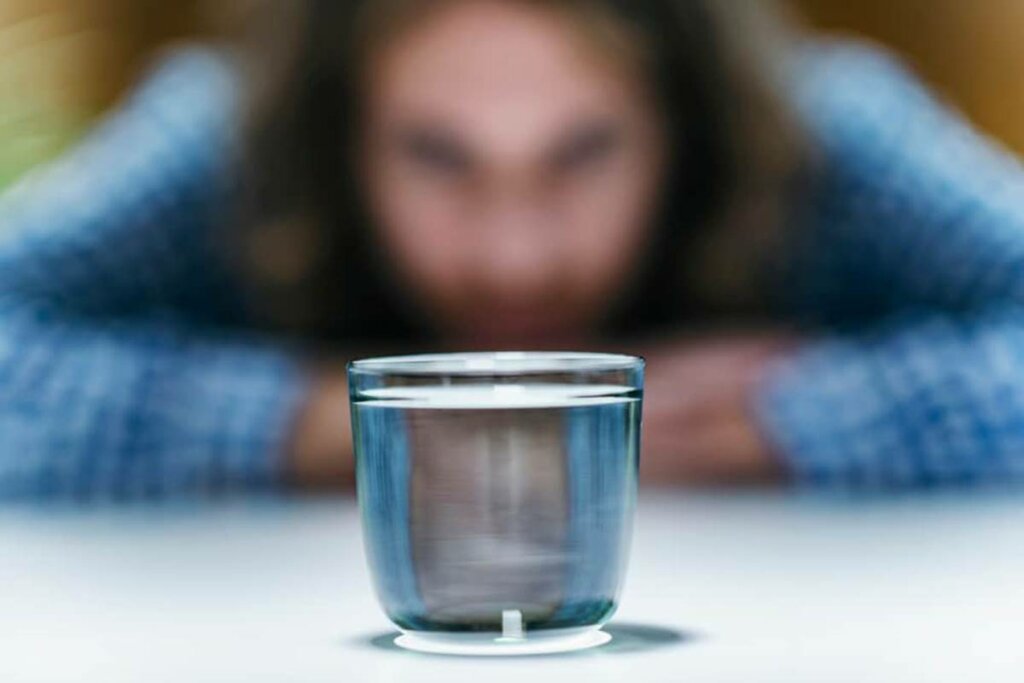 Mujer practicando la telequinesis con un vaso