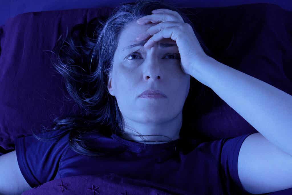 Mujer despierta en la cama sufriendo taquinesia