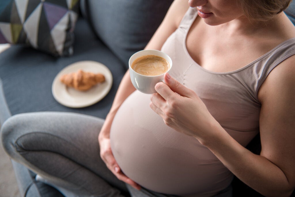 Zwangere vrouw met koffie en croissant