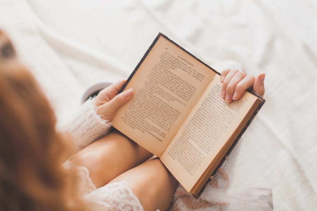 Donna che legge un libro a letto.