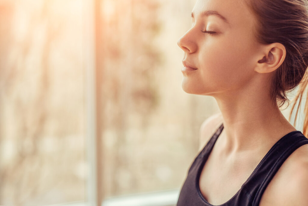 Woman with closed eyes near a window