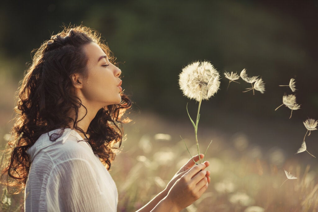 Woman blowing to fulfill the legend of the dandelion