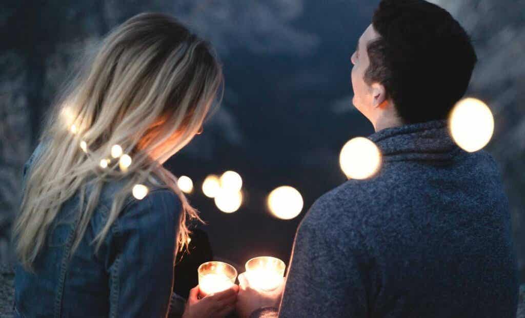 Pareja feliz rodeada de luces pensando en las preguntas para conocer mejor a tu pareja