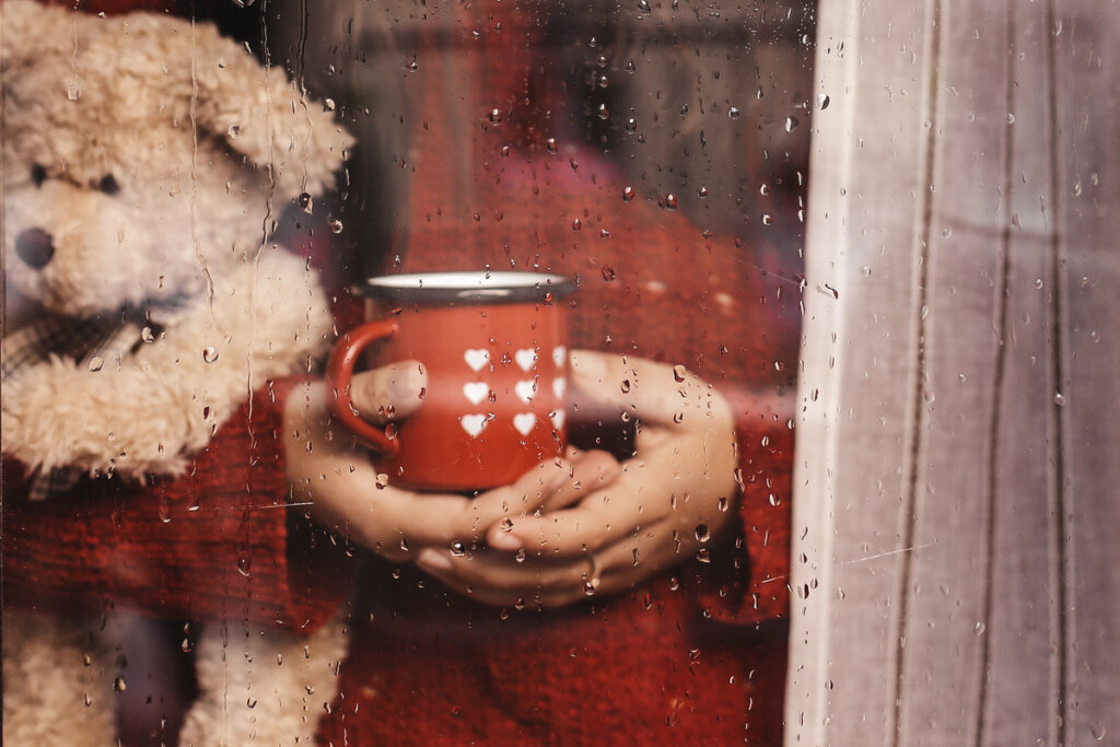 Persona viendo llover desde la ventana