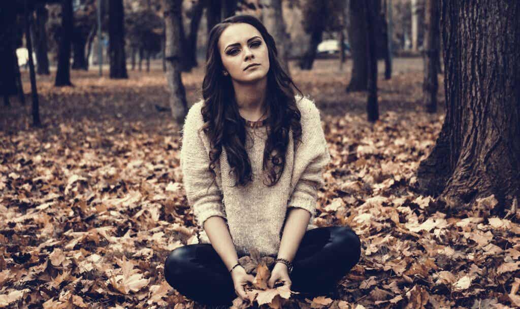 yaprakların üzerinde tek başına oturan üzgün kız