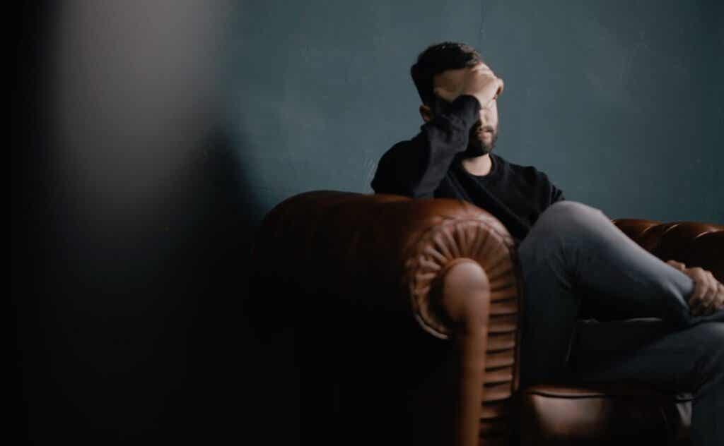 Hombre sentado en sofá que sufre vértigos psicógenos 