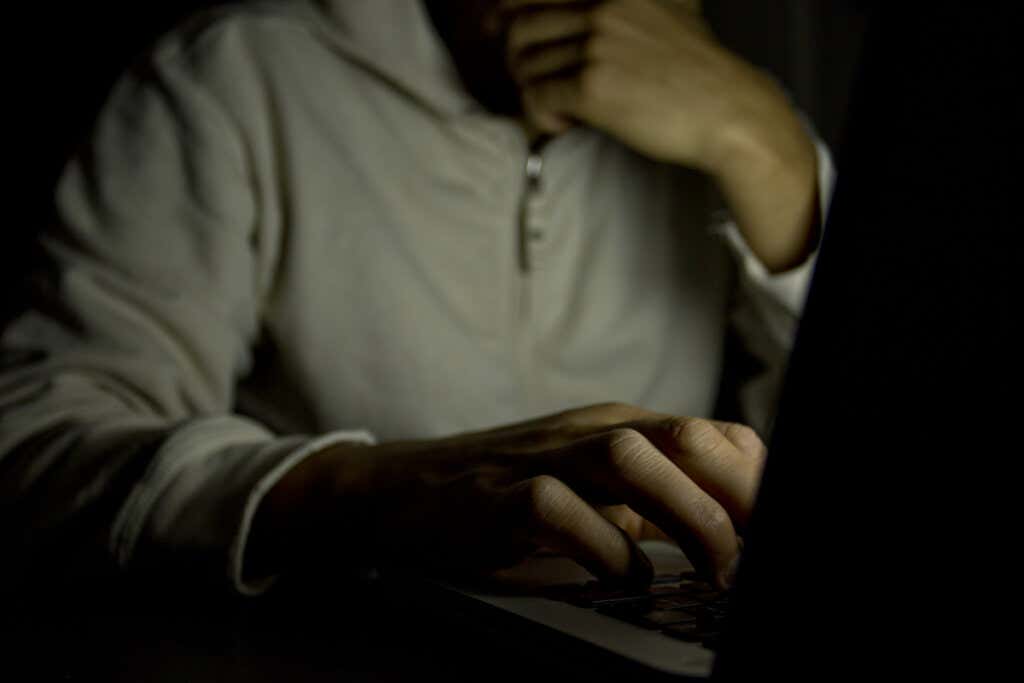 karanlıkta laptop ile oturan adam