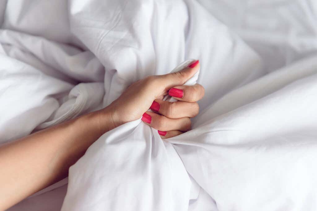 Mão de uma mulher agarrando lençóis