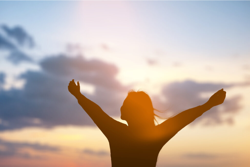 Mujer brazos abiertos observando el amanecer