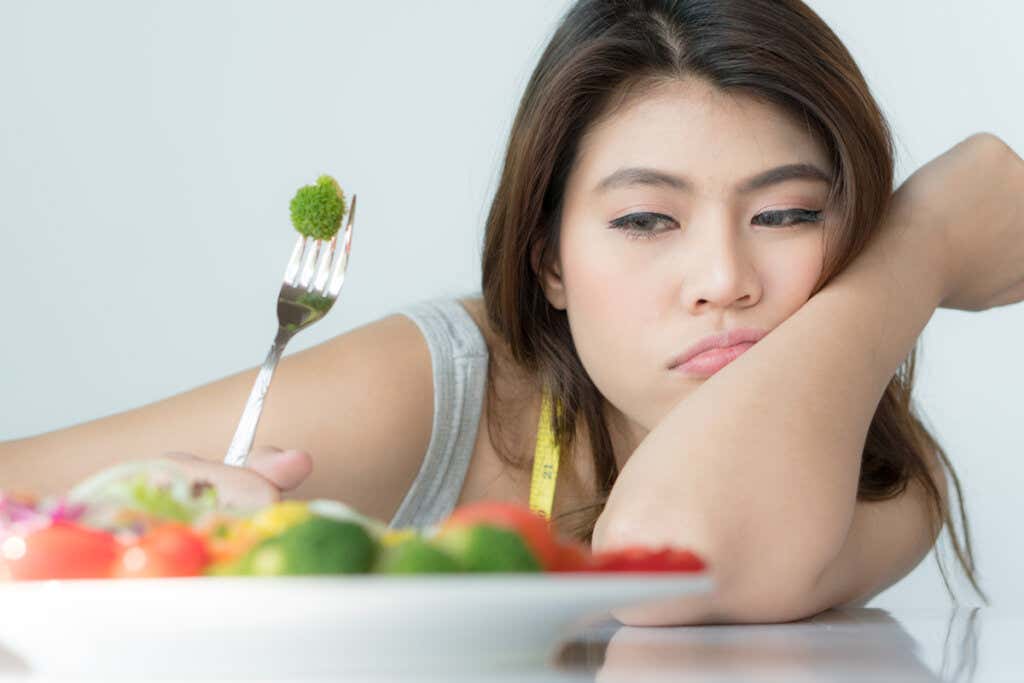 Mujer intentando comer vegetales